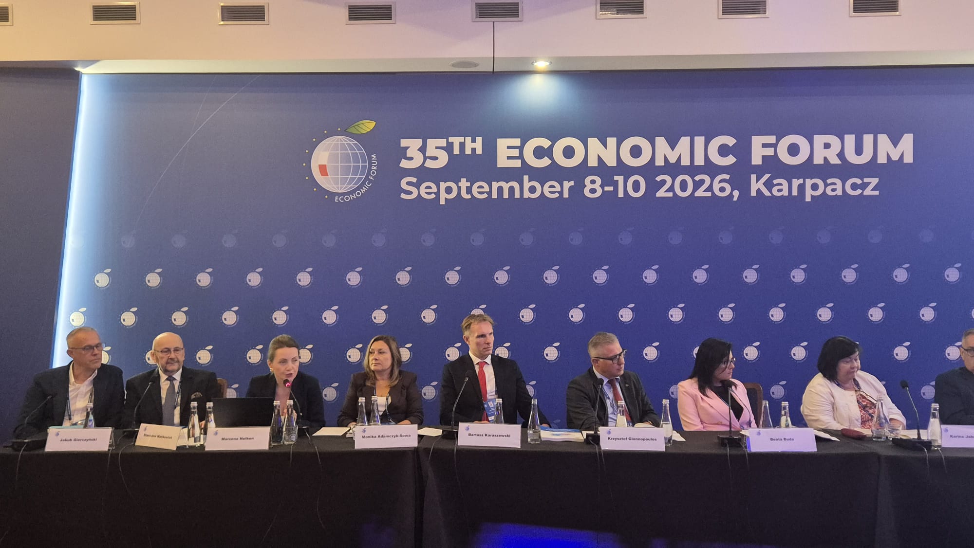 Uczestnicy panelu dyskusyjnego siedzą przy długim stole z mikrofonami podczas 35. Forum Ekonomicznego 2026 w Karpaczu. W tle znajduje się niebieska ścianka z nazwą i datą wydarzenia.
